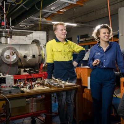 three people stand next to a table of wires and electronic equipment